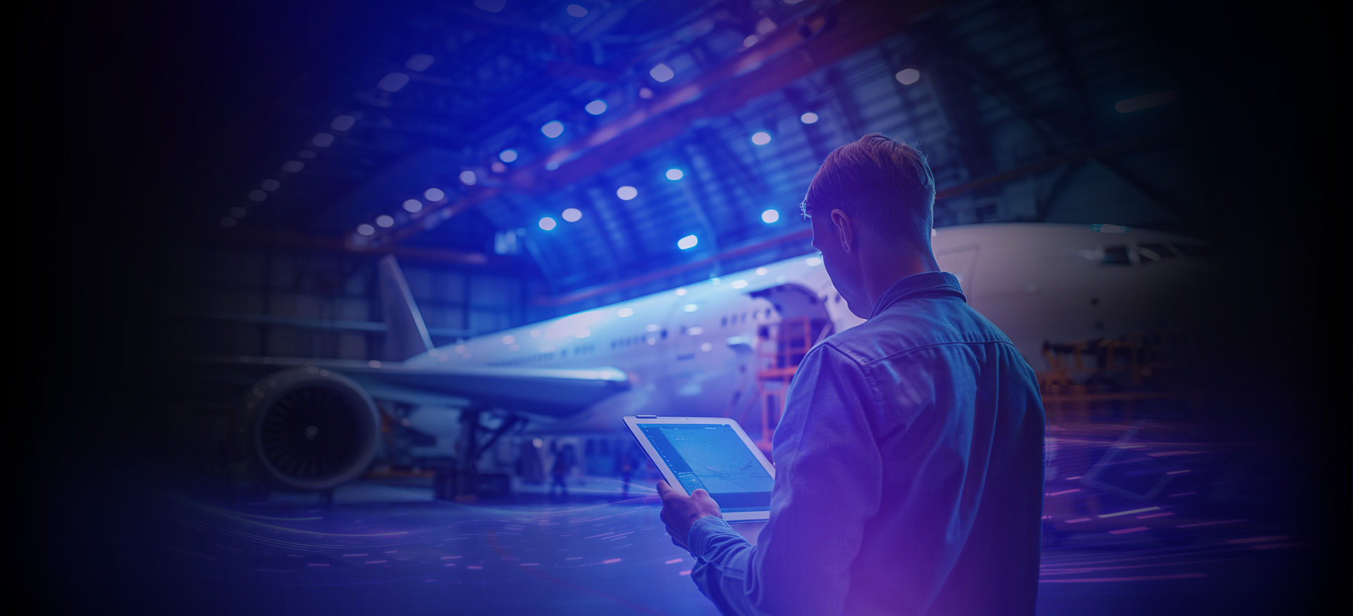 Person using tablet inspecting aircraft inside airplane hangar with jet in background