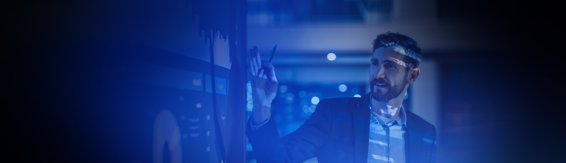 man touching a digital screen with blue and purple overlay over the image. He is looking at digital data