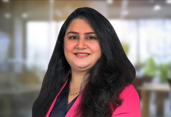 Smiling Indian woman with dark hair and brown eyes wearing a bright pink blazer